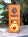 A box of 34° Original Crisps, Thin Light & Crunchy, standing upright on a weathered wooden surface with a blurred outdoor background of green foliage.