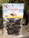 A 2 oz bag of Craft Market of Montana Buffalo Jerky, showing the dark brown jerky pieces inside a clear plastic pouch with a printed header card, set against a blurred outdoor background.