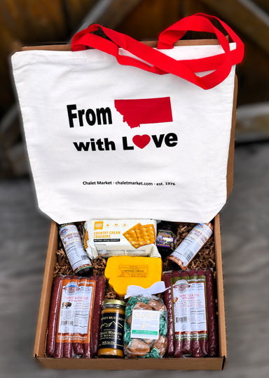A curated gift box filled with gourmet snacks and meats, featuring a white tote bag printed with 'From Utah with Love' and red handles, set in a cardboard box with shredded filler.