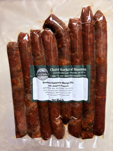 A vacuum-sealed package of smoked habanero mango sticks with jalapeños, showing multiple reddish-brown cured sticks inside clear plastic packaging with a front label reading Chalet Market of Montana.