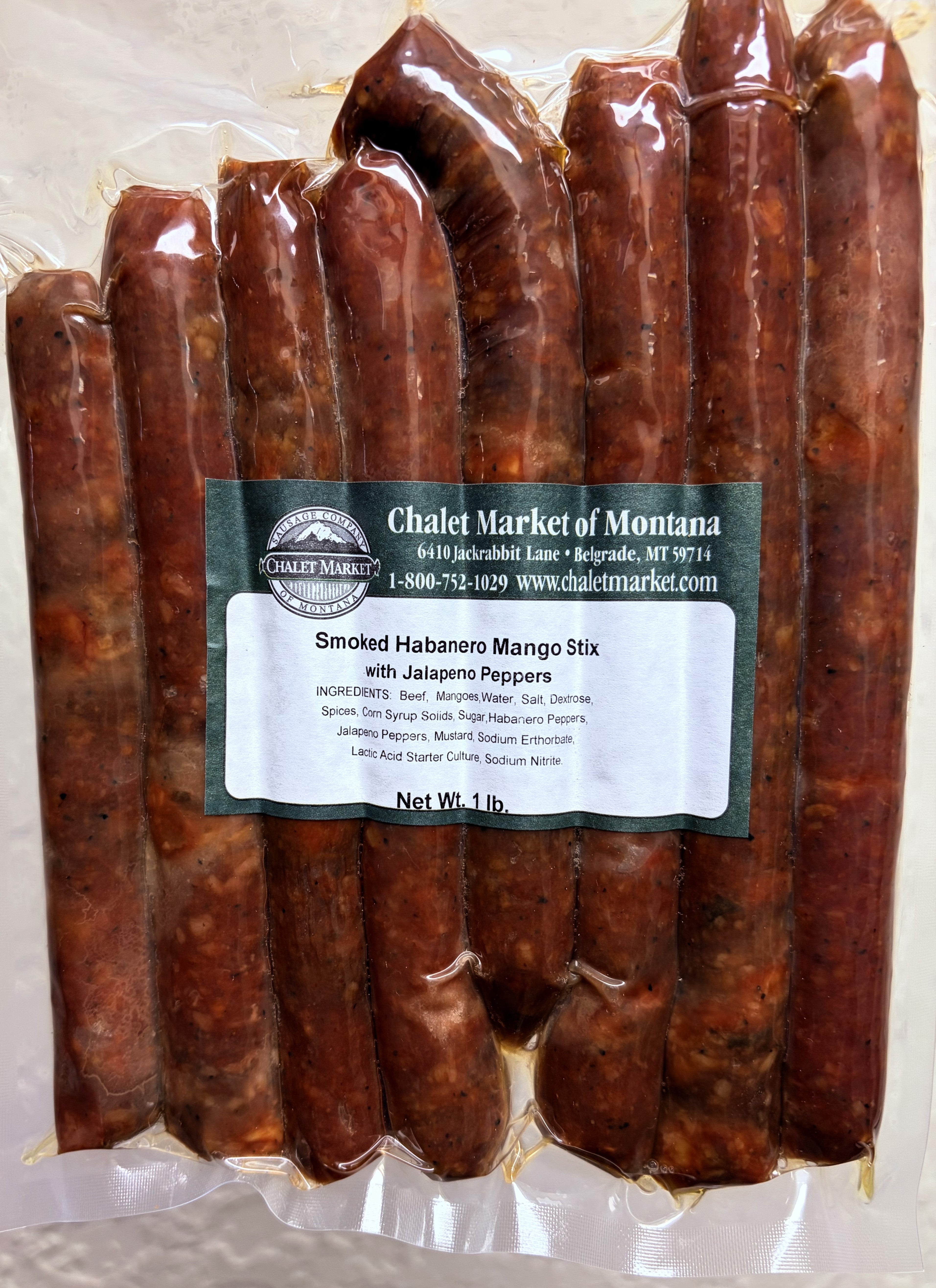 A vacuum-sealed package of smoked habanero mango stick with jalapeño peppers from Chalet Market of Montana, showing multiple reddish-brown cured sticks inside clear plastic packaging with a white and green label.